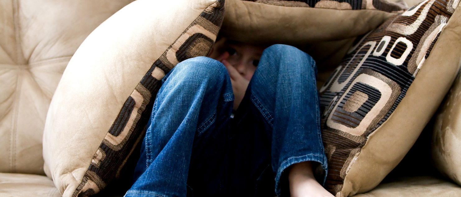 ein Junge versteckt sich auf dem Sofa unter vielen Kissen - Bild ist dekorativ