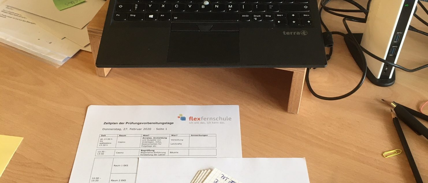ein Laptop zeigt das Bild der Flex-Homepage. Davor liegen handgeschriebene Karteikarten und verschiedene Papiere.