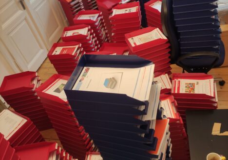 mehrere Stapel mit Ablagekörben, die mit Lernbriefen der Flex-Fernschule gefüllt sind