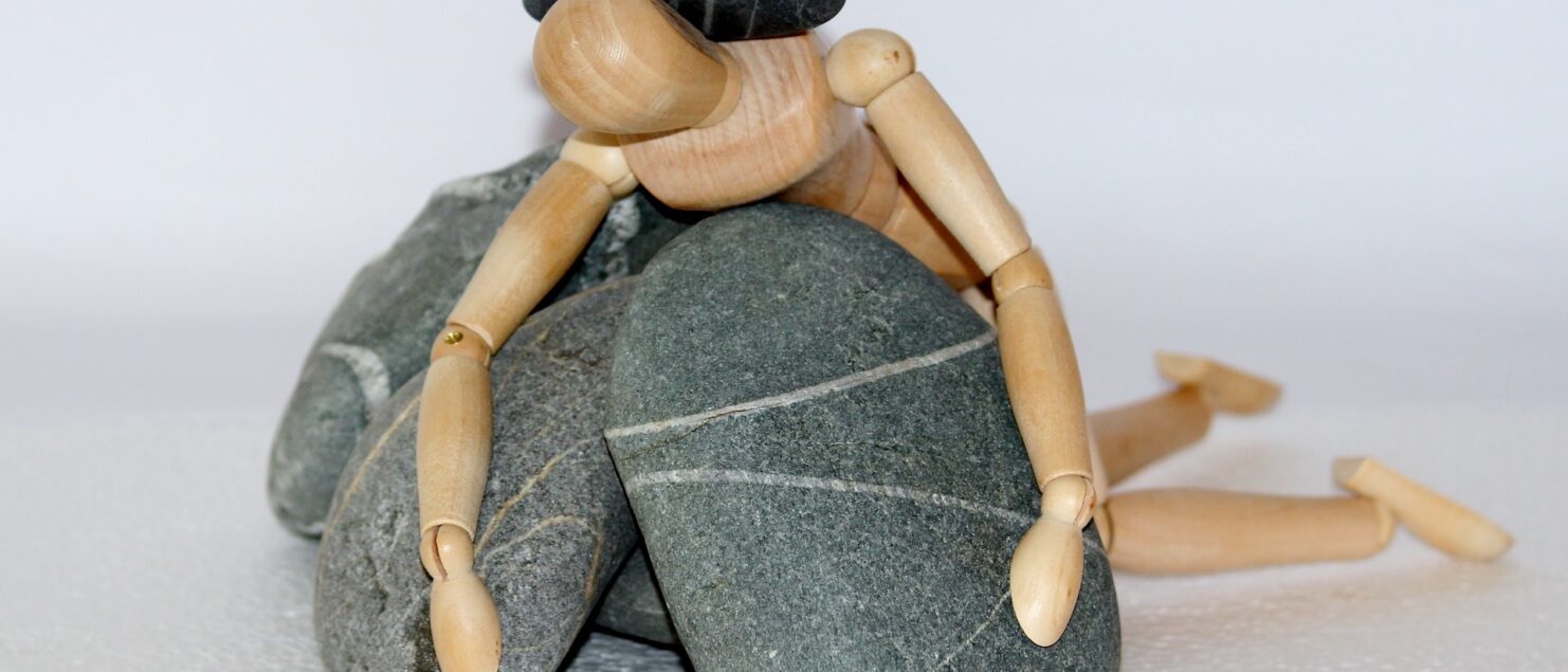 eine Holzpuppe ist unter Steinen begraben - Bild ist dekorativ